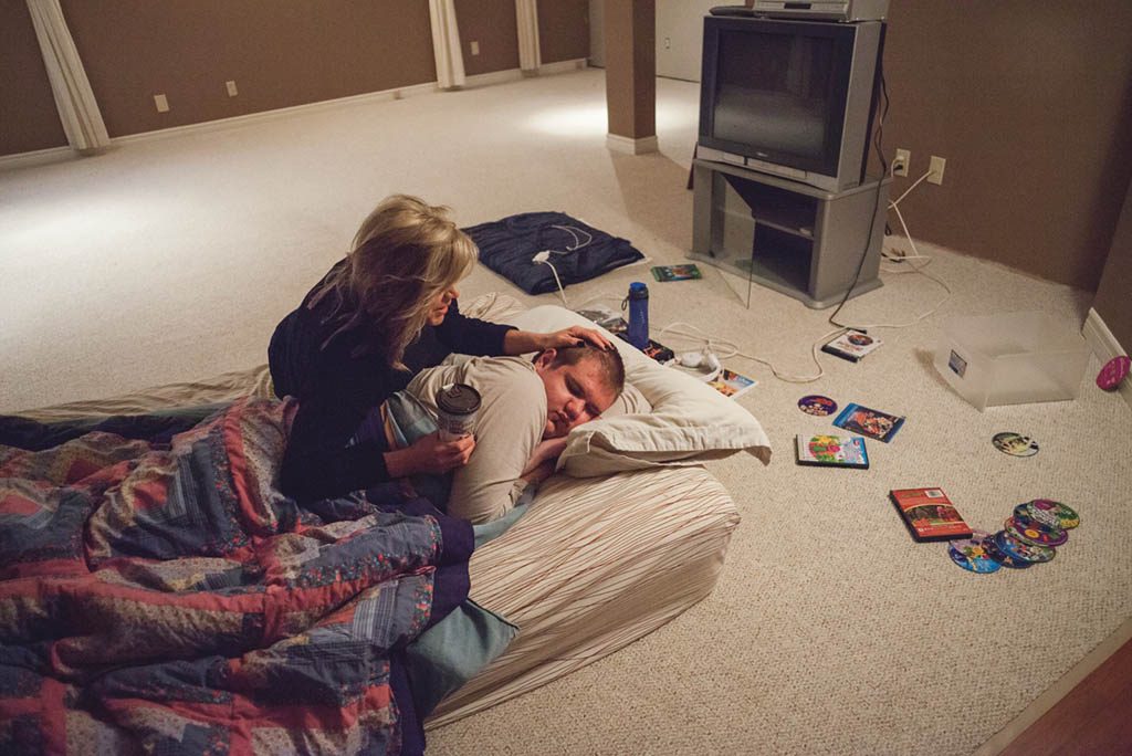 image of a woman comforting a young man on a mattress on the floor
